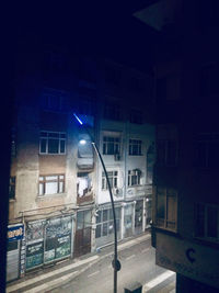 Illuminated street amidst buildings at night