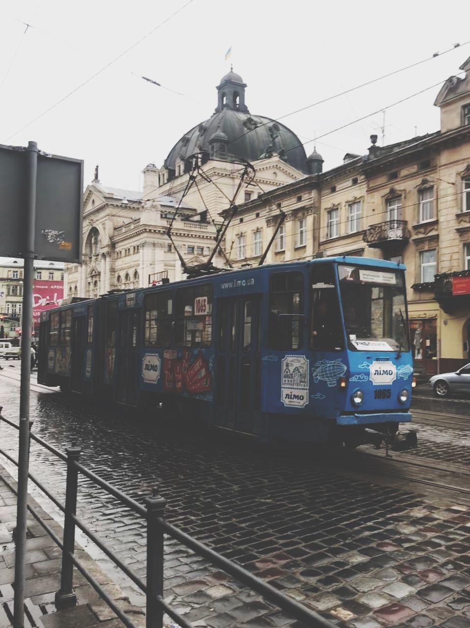 TRAIN ON CITY STREET AGAINST SKY