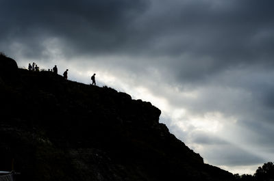 View of people on mountain against cloudy sky