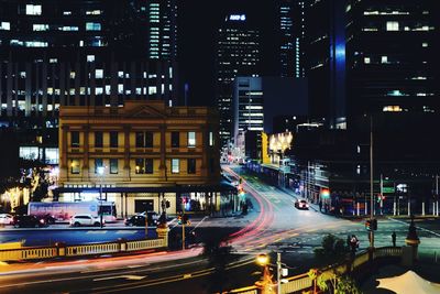 High angle view of light trails on city street by buildings at night