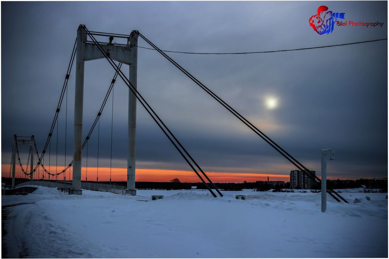 SNOW COVERED BRIDGE AGAINST SKY DURING SUNSET