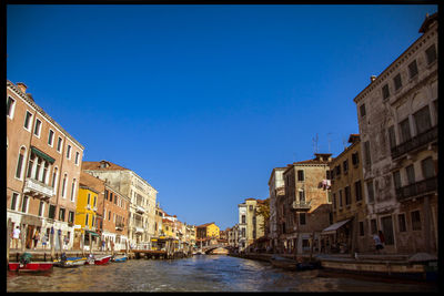 Buildings in city against clear blue sky