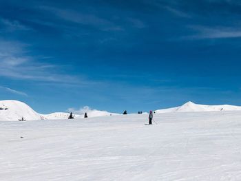 Woman skiing on snow covered land against sky