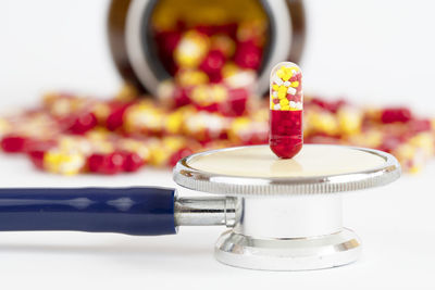 Antibiotic drug capsule fall from bottle with stethoscope on white background