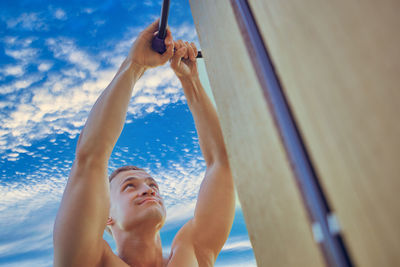 Low angle view of young woman exercising against sky