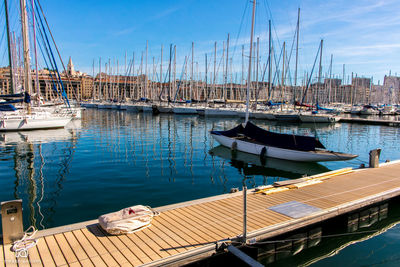 Sailboats moored at harbor against sky