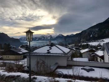 Houses by snow covered mountains against sky