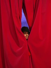 Portrait of man wearing hat looking through stage curtain