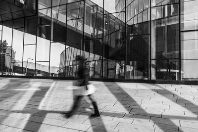 Blurred motion of people walking on footpath by street in city