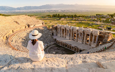 Hierapolis ancient city pamukkale turkey, young woman with hat watching sunset by the ruins unesco