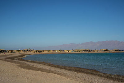 Scenic view of beach against clear blue sky