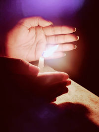 Close-up of hand holding lit candle