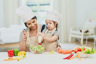 Female friends and vegetables in kitchen at home