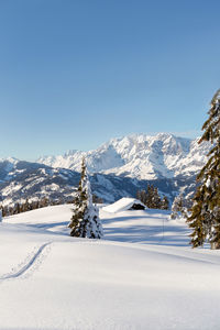 Beautiful winter mountain landscape with snow tracks to the alpine hut