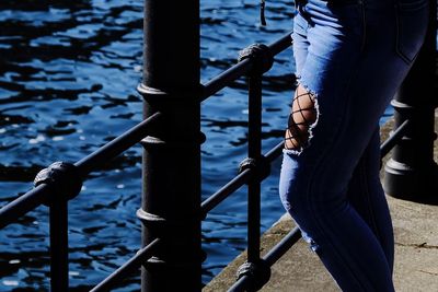 Low section of man holding railing in city