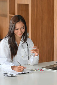 Smiling young doctor prescribing medicine at clinic