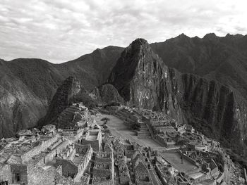 High angle view of old ruins by mountains against cloudy sky