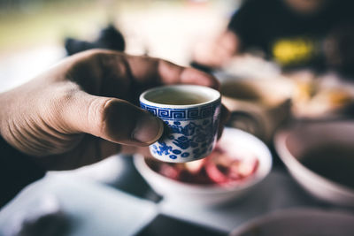 Midsection of person holding coffee cup on table