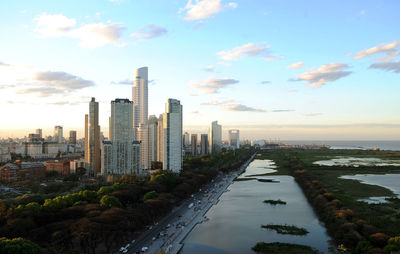 Modern buildings in city against sky during sunset