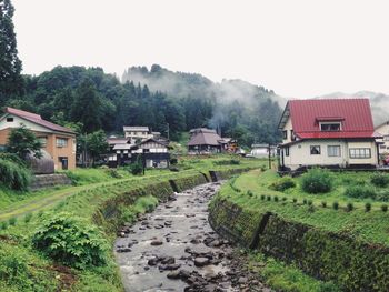 Houses by agricultural field against sky