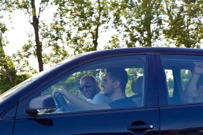 Portrait of man sitting with friend in car seen through window