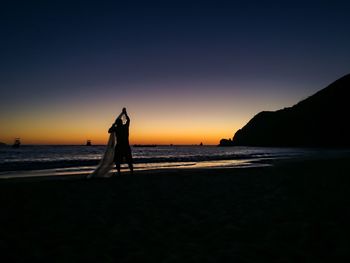 Silhouette people on beach at sunset