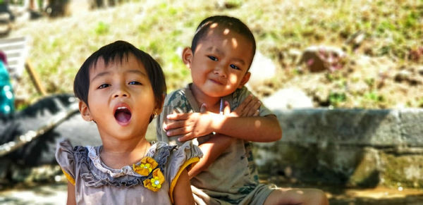 Portrait of smiling siblings sitting outdoors