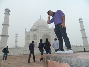 Tourists at temple against clear sky