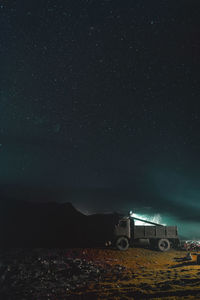 Illuminated car on field against sky at night