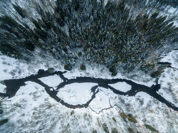 Aerial view of stream flowing amidst snow covered land