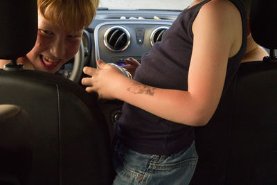 Midsection of boy standing in car