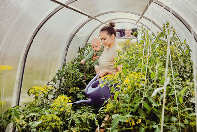 Portrait of young woman standing by plants