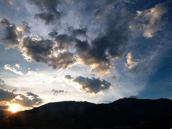 Sun shining through clouds over mountains