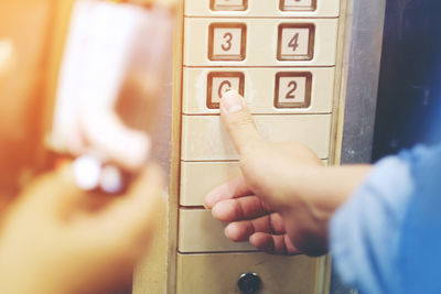 Cropped hand of woman pressing push button in elevator