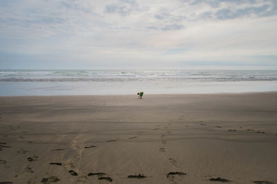 Boy playing at beach against sky