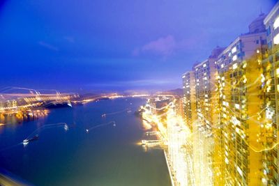 Illuminated cityscape by sea against sky at night