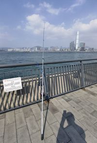 Railing by sea against sky in city