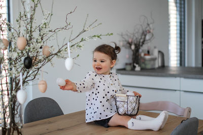 Portrait of cute girl sitting on table at home