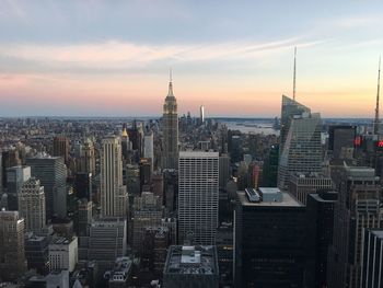 Aerial view of buildings in city against cloudy sky