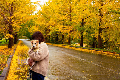 Rear view of woman with dog on road