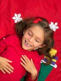 Little girl dreaming about christmas wish list eyes closed christmas red background white snowflakes 