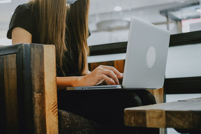 Midsection of woman using mobile phone while sitting on table