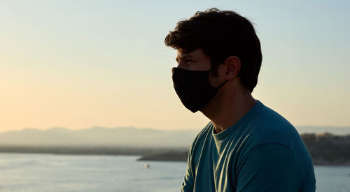 Portrait of young man standing in sea against sky