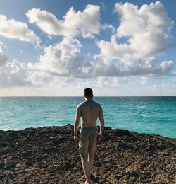 Rear view of shirtless man standing on beach