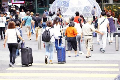 Rear view of people walking on road in city