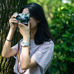 Midsection of man photographing against tree