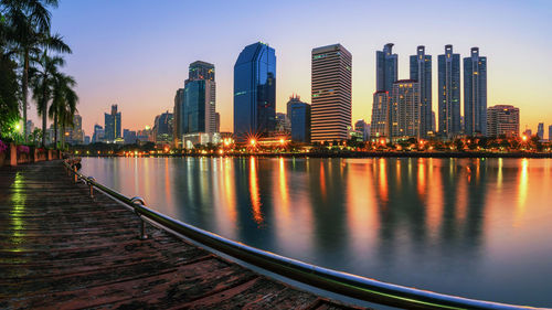 Sea by illuminated buildings against sky in city