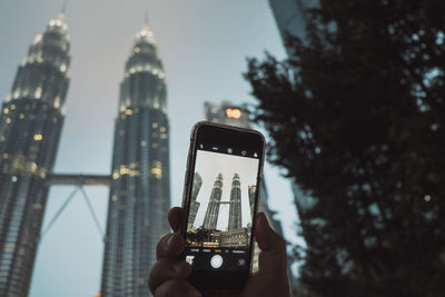 Low angle view of person using smart phone against sky