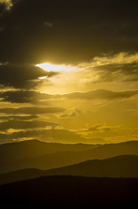 Scenic view of silhouette mountains against romantic sky at sunset