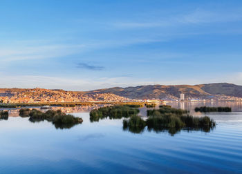 Scenic view of lake by buildings against blue sky